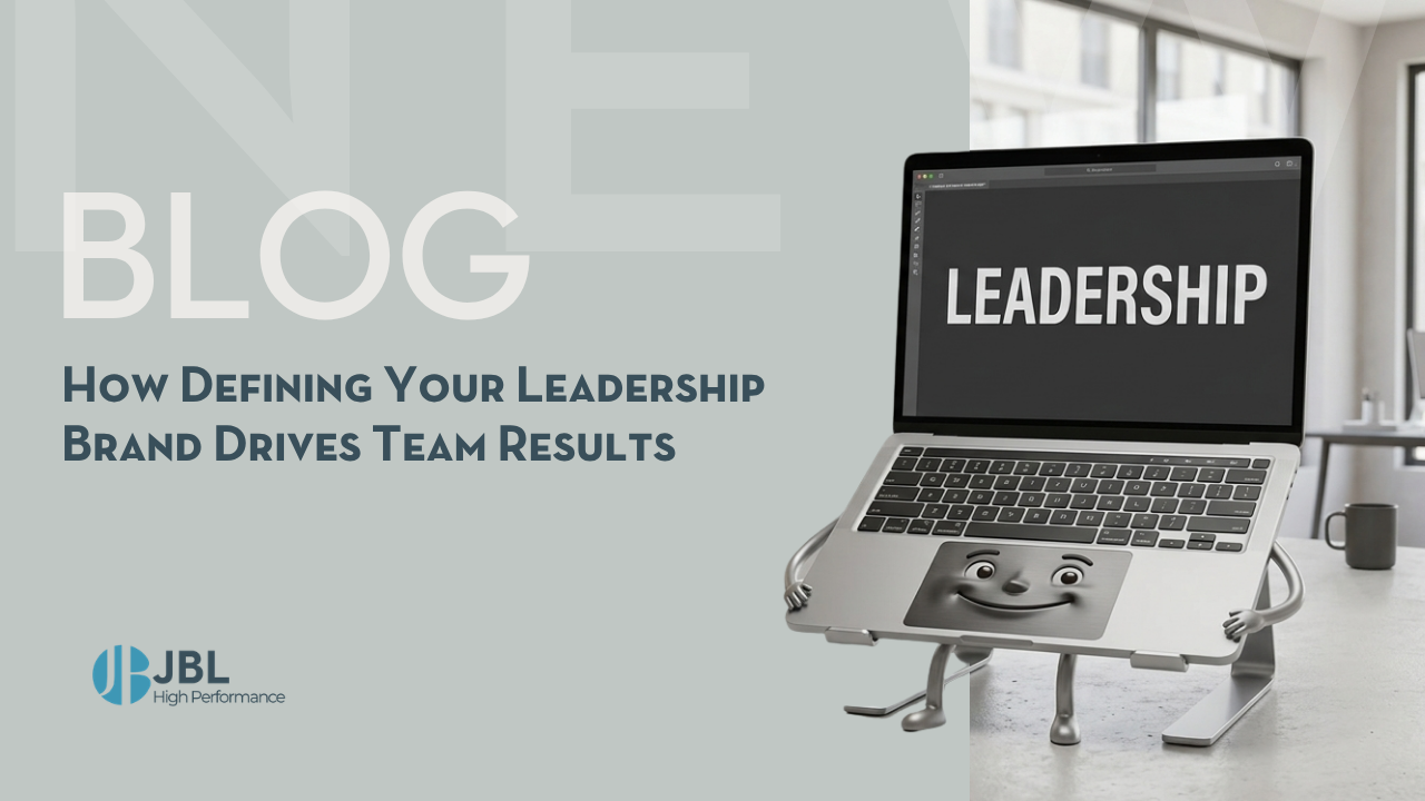 A smiling laptop with arms and legs stands on a desk showing the word leadership on its screen alongside blog title about defining leadership brand driving team results
