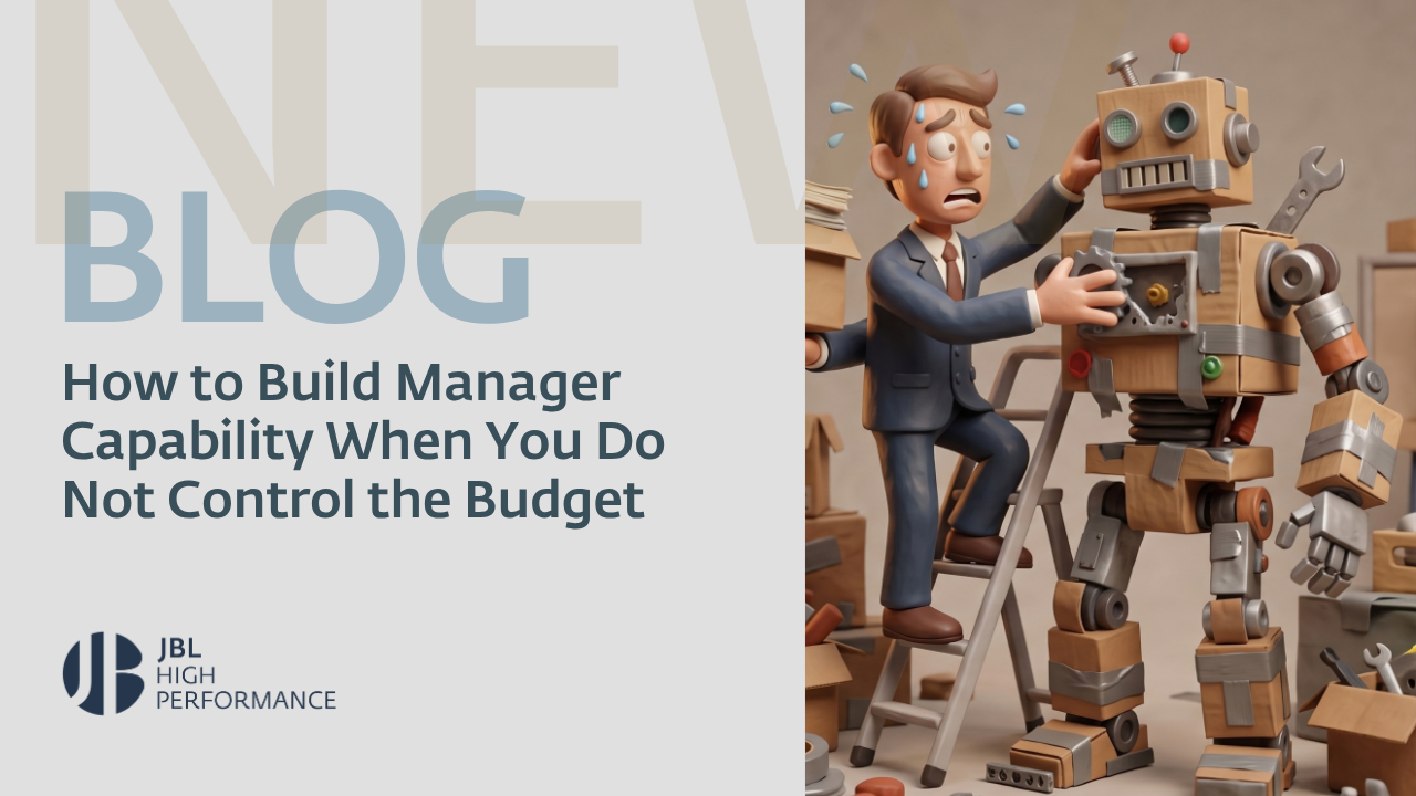 A stressed businessman on a ladder tries to fix a large cardboard robot with tools around, illustrating challenges in building manager capability without budget control.